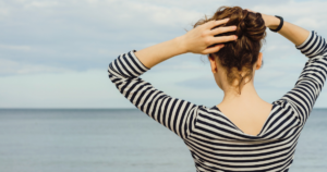 海を眺めながら立つ40代女性の後ろ姿・頭皮と髪の健康を考える美容師の想い