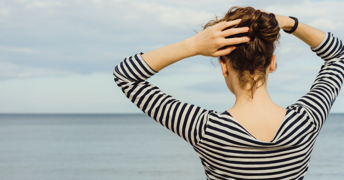 海を眺めながら立つ40代女性の後ろ姿・頭皮と髪の健康を考える美容師の想い